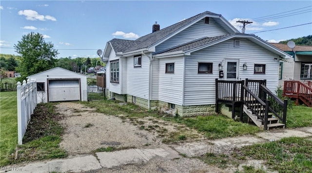 17 Spring St, Dennison, OH 44621 - view of front facade featuring driveway, a shingled roof, fence, an outdoor structure, and a garage