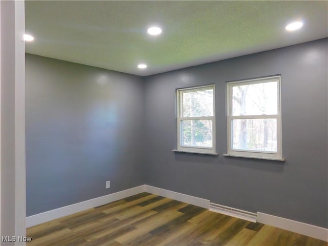 empty room with baseboards, recessed lighting, and wood finished floors