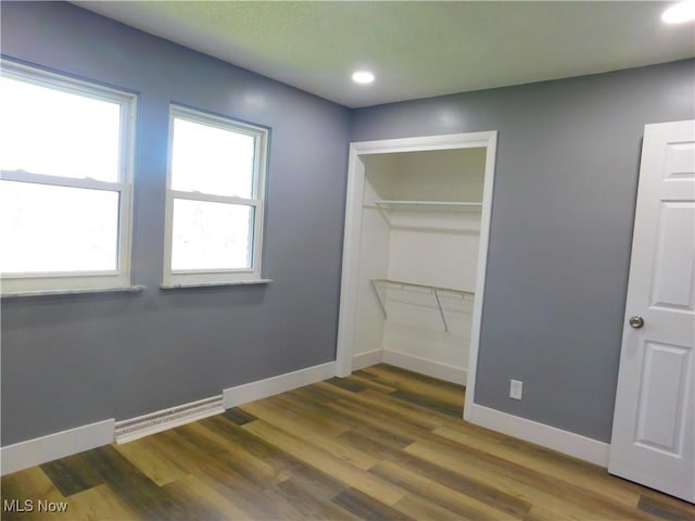 unfurnished bedroom featuring wood finished floors, recessed lighting, and baseboards