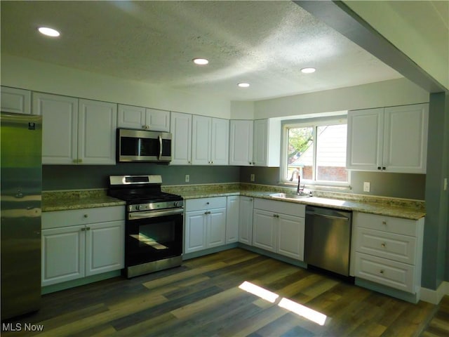 kitchen featuring stainless steel appliances, a sink, white cabinets, recessed lighting, and a textured ceiling