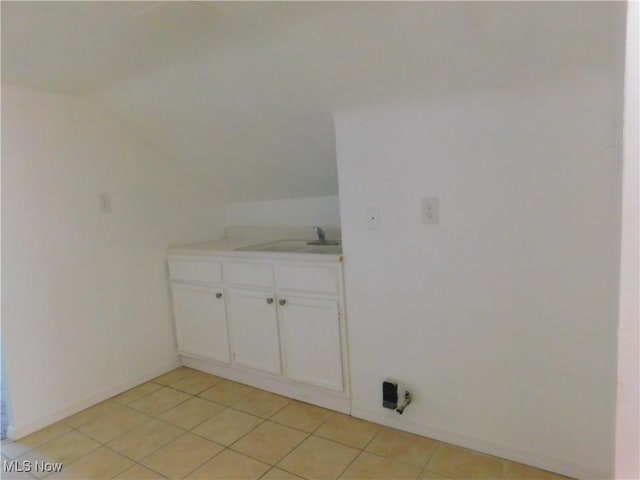 washroom featuring a sink, light tile patterned floors, and baseboards