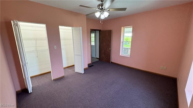 6255 Highland Ridge Rd, Lowell, OH 45744 - unfurnished bedroom featuring two closets, dark colored carpet, ceiling fan, and baseboards
