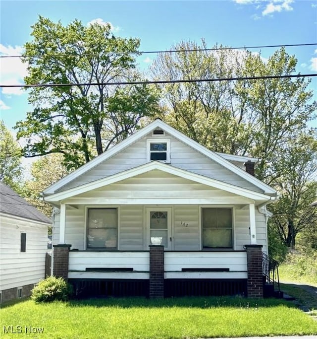 shotgun-style home featuring covered porch and a front lawn