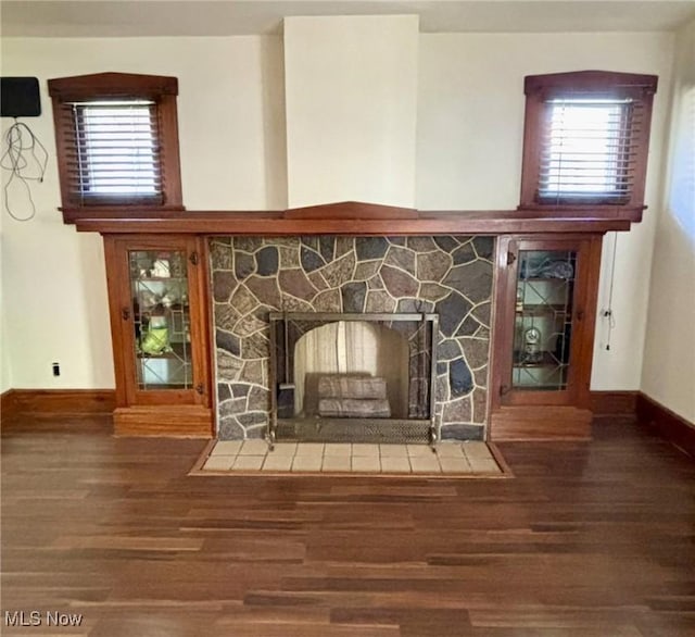 detailed view of wood finished floors, baseboards, and a fireplace