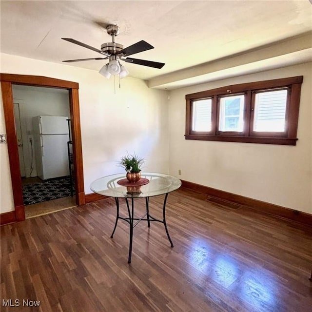 dining room featuring dark wood finished floors, baseboards, and ceiling fan