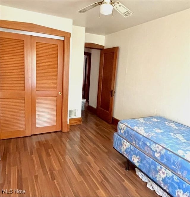bedroom with wood finished floors, a closet, ceiling fan, and baseboards