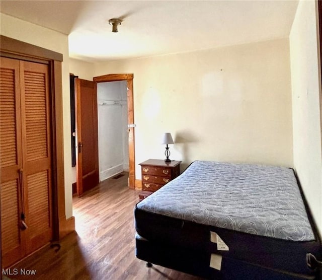 bedroom with wood finished floors, a closet, and baseboards
