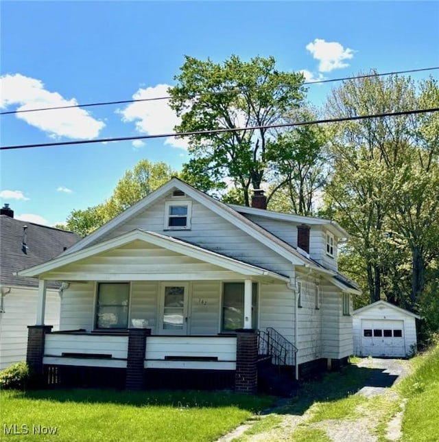 view of front of home featuring an outbuilding, a chimney, a garage, and covered porch