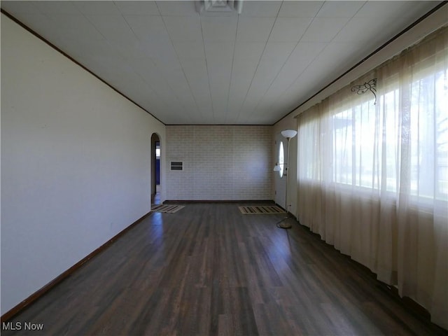 111 Pine Ln, Barnesville, OH 43713 - empty room with arched walkways, wood finished floors, brick wall, and baseboards