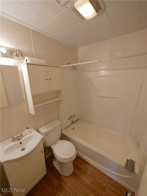 111 Pine Ln, Barnesville, OH 43713 - bathroom with toilet, tub / shower combination, wood finished floors, vanity, and tile walls
