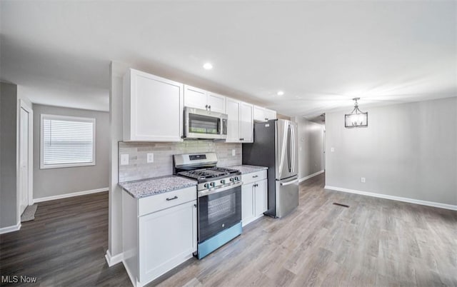 1527 Carterland Dr, Ashtabula, OH 44004 - kitchen with appliances with stainless steel finishes, baseboards, light wood-style flooring, white cabinets, and tasteful backsplash