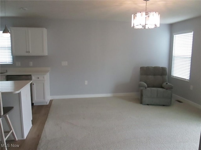 unfurnished room with a chandelier, light carpet, and baseboards