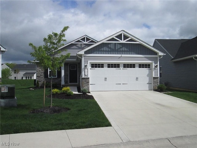 craftsman house featuring stone siding, a garage, a front yard, driveway, and board and batten siding
