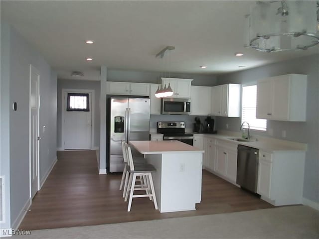 kitchen with appliances with stainless steel finishes, a sink, a center island, white cabinets, and recessed lighting