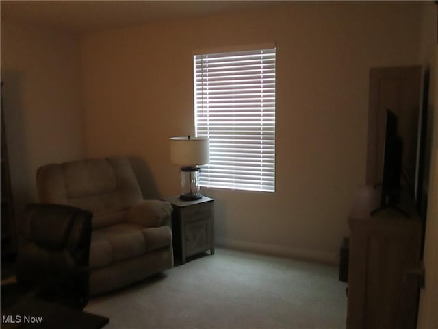 living area featuring light colored carpet and baseboards