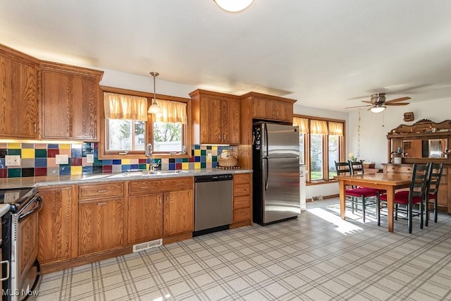 7101 Reynolds Rd, Mentor, OH 44060 - kitchen featuring appliances with stainless steel finishes, a sink, brown cabinetry, backsplash, and a ceiling fan