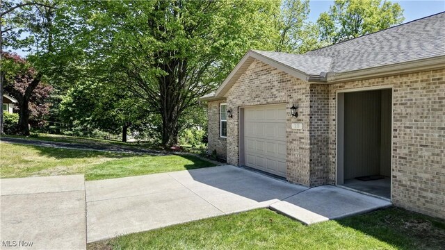213 Knollton Dr, Millersburg, OH 44654 - view of side of property featuring roof with shingles, brick siding, an attached garage, and a lawn