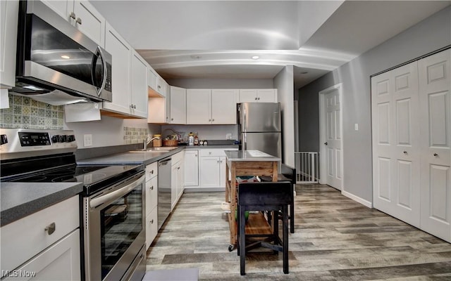 213 Knollton Dr, Millersburg, OH 44654 - kitchen featuring appliances with stainless steel finishes, light wood-style floors, white cabinets, tasteful backsplash, and a sink