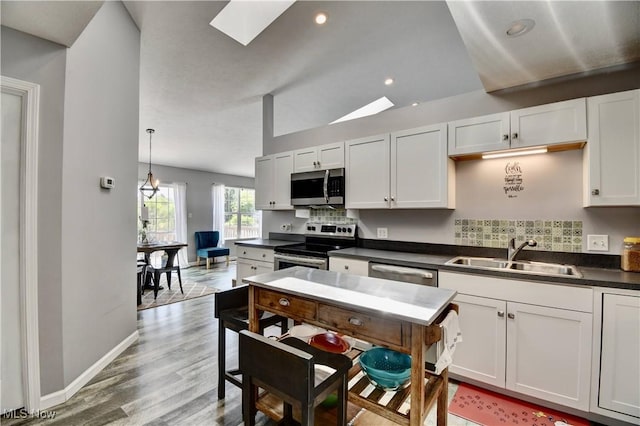 213 Knollton Dr, Millersburg, OH 44654 - kitchen with a sink, appliances with stainless steel finishes, dark countertops, a skylight, and decorative backsplash