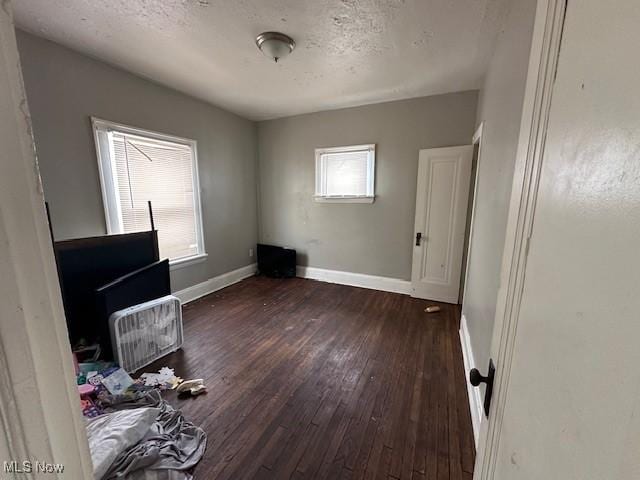 unfurnished bedroom with dark wood-style floors, baseboards, and a textured ceiling