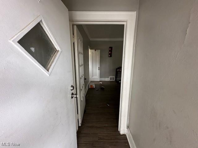 corridor with wood finished floors, baseboards, and ornamental molding