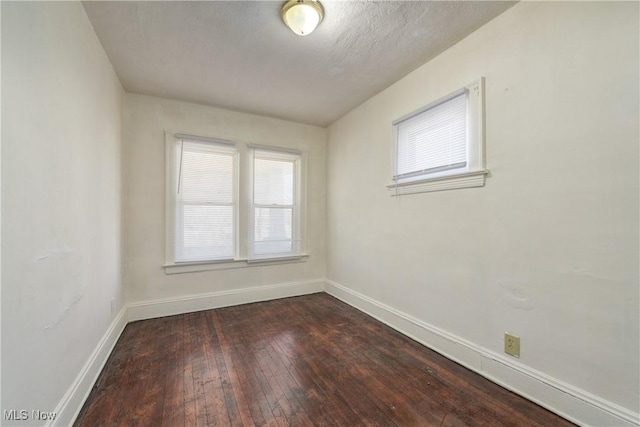 unfurnished room with dark wood-type flooring and baseboards