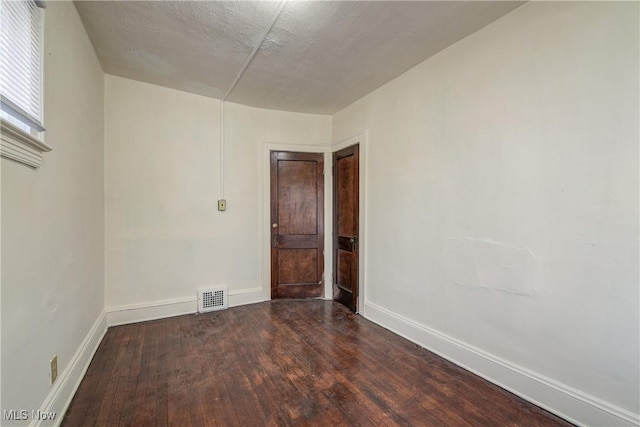 unfurnished room featuring dark wood-type flooring and baseboards