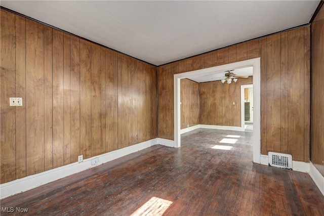 unfurnished room featuring hardwood / wood-style floors, ceiling fan, and wooden walls