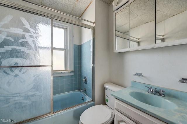 full bathroom with healthy amount of natural light, toilet, vanity, and a drop ceiling