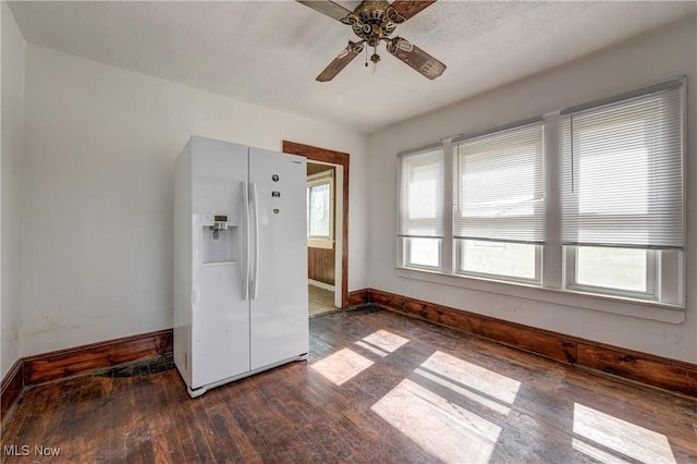 spare room with dark wood-type flooring, ceiling fan, and baseboards
