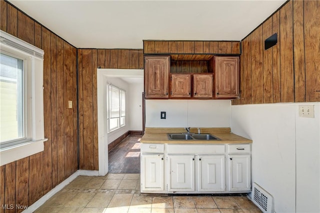 kitchen featuring a sink, light countertops, white cabinets, and baseboards