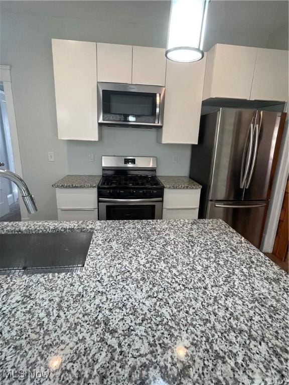 3217 W 14th St, Cleveland, OH 44109 - kitchen with appliances with stainless steel finishes, light stone counters, a sink, and white cabinets