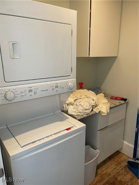 3217 W 14th St, Cleveland, OH 44109 - laundry room with stacked washer and clothes dryer, dark wood-type flooring, cabinet space, and baseboards