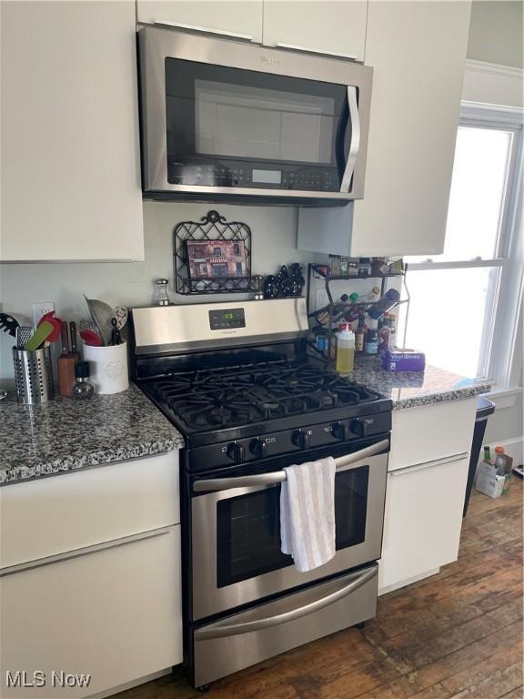 3217 W 14th St, Cleveland, OH 44109 - kitchen with appliances with stainless steel finishes, white cabinetry, dark wood-type flooring, and light stone counters