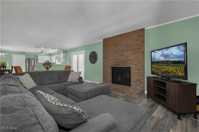 1060 S Watkins Rd, Alexandria, OH 43001 - living room featuring a textured ceiling, a brick fireplace, wood finished floors, and a chandelier