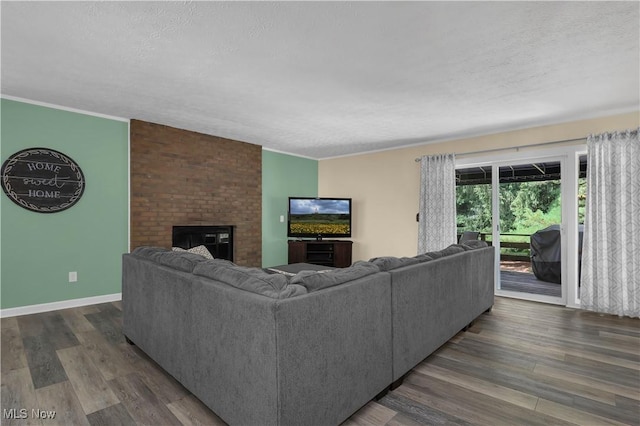 1060 S Watkins Rd, Alexandria, OH 43001 - living room featuring a textured ceiling, a brick fireplace, dark wood-style flooring, and baseboards