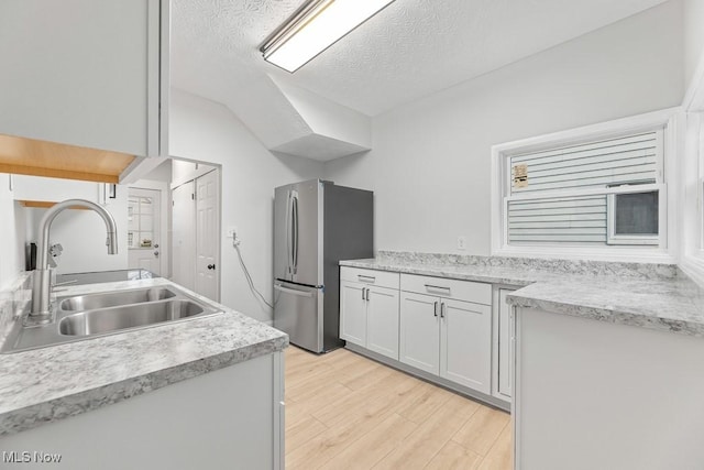 38 W Washington St, Alliance, OH 44601 - kitchen with freestanding refrigerator, a sink, light wood-style flooring, light countertops, and a textured ceiling