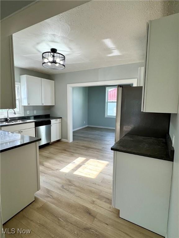 1226 E Main St, Coshocton, OH 43812 - kitchen featuring appliances with stainless steel finishes, a sink, dark countertops, white cabinets, and light wood-style floors