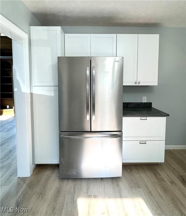 1226 E Main St, Coshocton, OH 43812 - kitchen with freestanding refrigerator, light wood-style floors, dark countertops, white cabinetry, and a textured ceiling