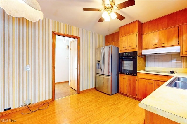 2455 Alexander Mnr E, Steubenville, OH 43952 - kitchen with black appliances, under cabinet range hood, light wood finished floors, light countertops, and brown cabinets