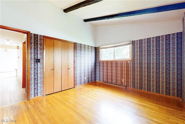 2455 Alexander Mnr E, Steubenville, OH 43952 - unfurnished bedroom with wood finished floors, wallpapered walls, a baseboard heating unit, beamed ceiling, and baseboards