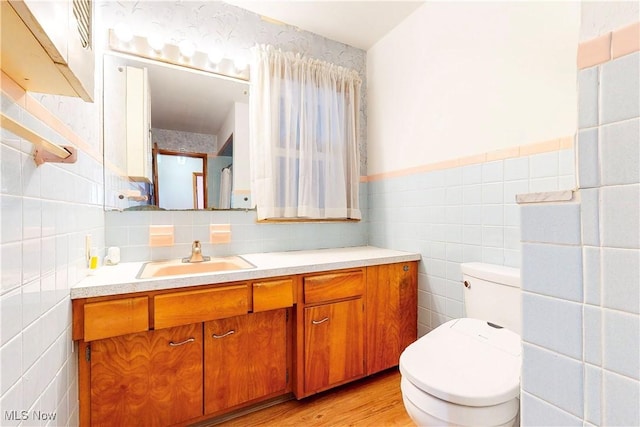 2455 Alexander Mnr E, Steubenville, OH 43952 - bathroom featuring tile walls, toilet, vanity, wood finished floors, and wainscoting