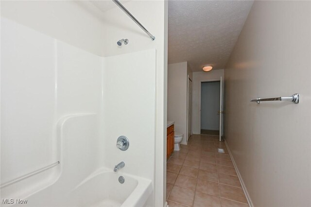 4212 Castle Rdg, Copley, OH 44321 - bathroom with tile patterned floors, a textured ceiling, toilet, shower / washtub combination, and baseboards