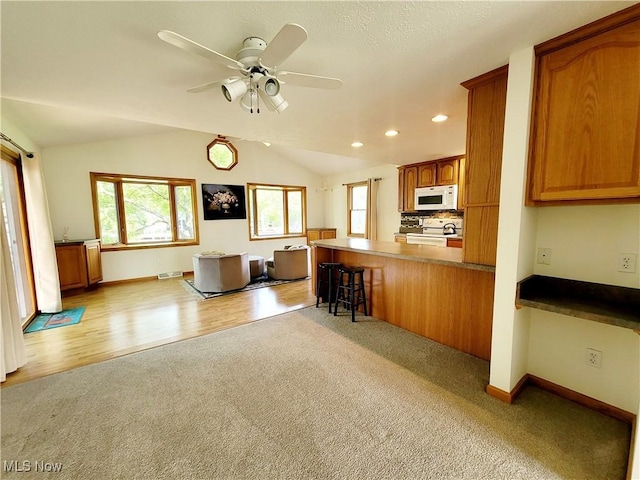 kitchen with white appliances, light colored carpet, a peninsula, open floor plan, and ceiling fan