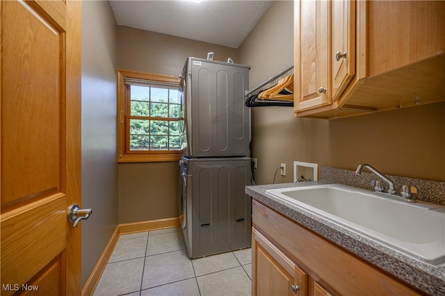 6240 Tim Dr, Wadsworth, OH 44281 - laundry room featuring stacked washer and clothes dryer, cabinet space, light tile patterned flooring, baseboards, and a textured ceiling