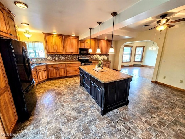 105 W 40th St, Shadyside, OH 43947 - kitchen with black appliances, arched walkways, brown cabinetry, a center island, and tasteful backsplash
