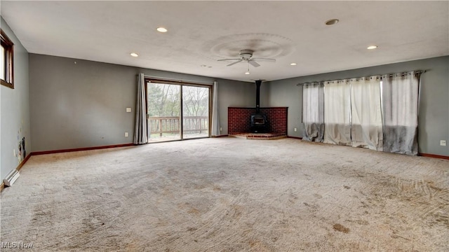 6456 Dover Zoar Rd NE, Dover, OH 44622 - unfurnished living room featuring a wood stove, baseboards, recessed lighting, carpet, and ceiling fan