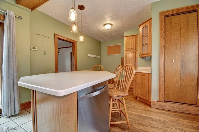 6456 Dover Zoar Rd NE, Dover, OH 44622 - kitchen featuring dishwasher, a breakfast bar area, light countertops, a textured ceiling, and glass insert cabinets
