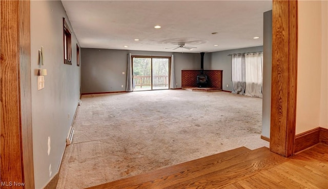 6456 Dover Zoar Rd NE, Dover, OH 44622 - unfurnished living room featuring a wood stove, recessed lighting, baseboards, and carpet