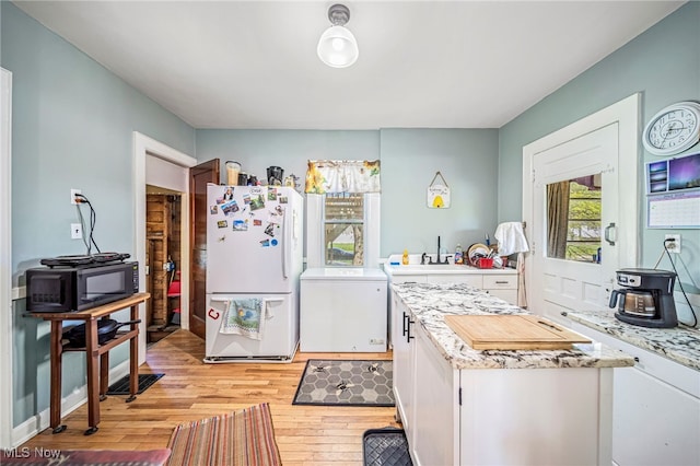 2226 W 13th St, Ashtabula, OH 44004 - kitchen featuring freestanding refrigerator, black microwave, light wood-type flooring, light countertops, and a sink